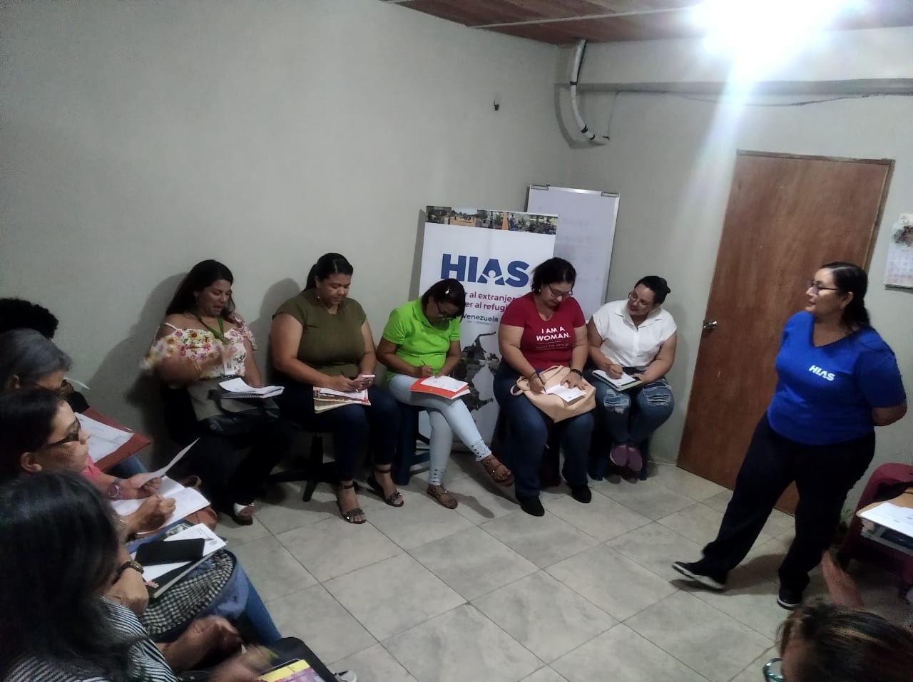 man wearing a black jacket, white shirt, blue jeans, and brown boots, playing a white electric guitar while sitting on an amp